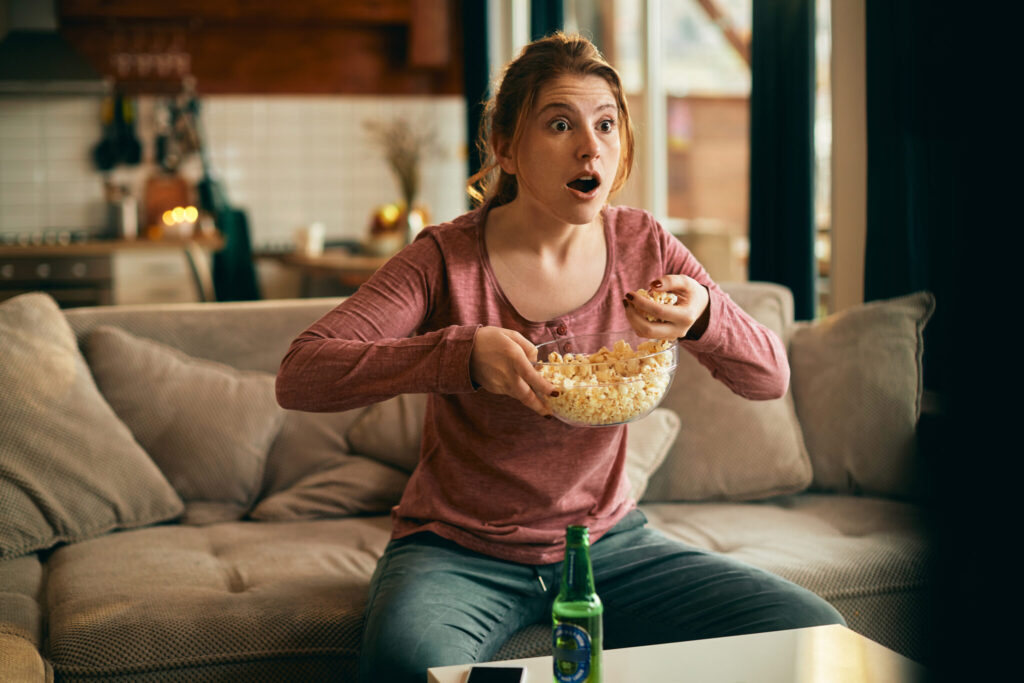 young woman eating popcorn while watching disbelief something tv scaled 1
